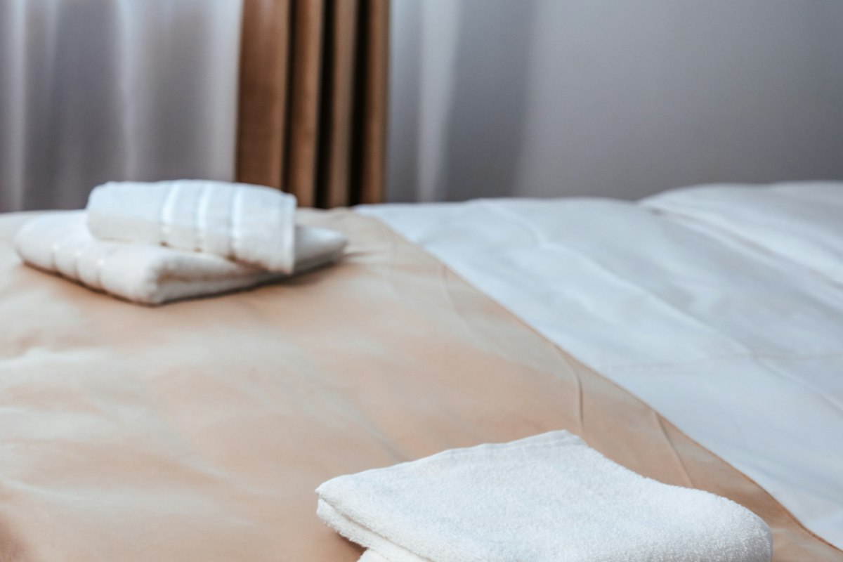 Fresh folded white towels on a neatly made guest bed