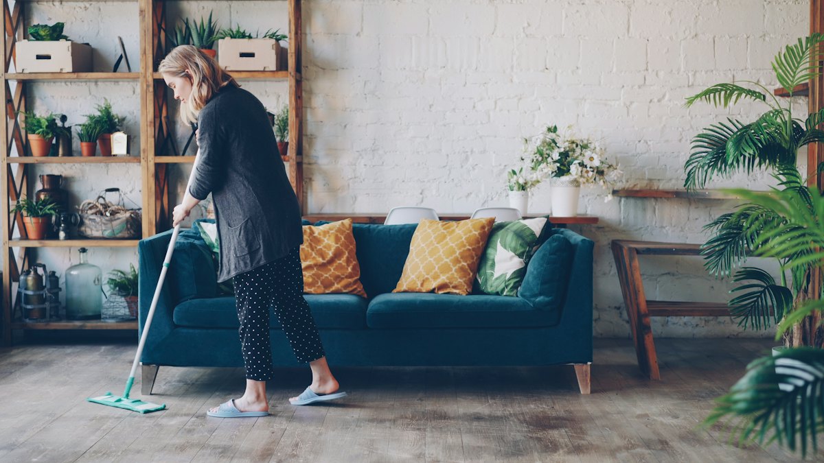 Housekeeper mopping the floor of a bright living room